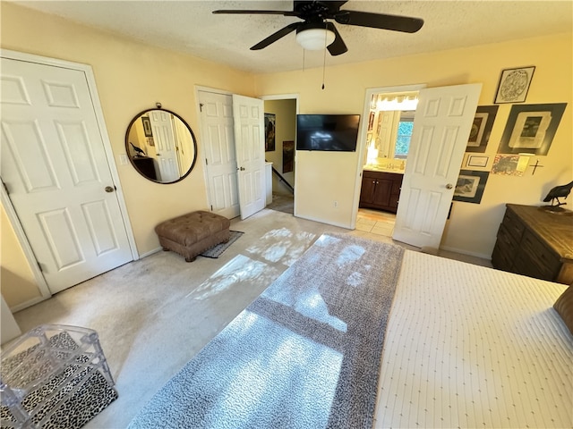 carpeted bedroom featuring ceiling fan and ensuite bath