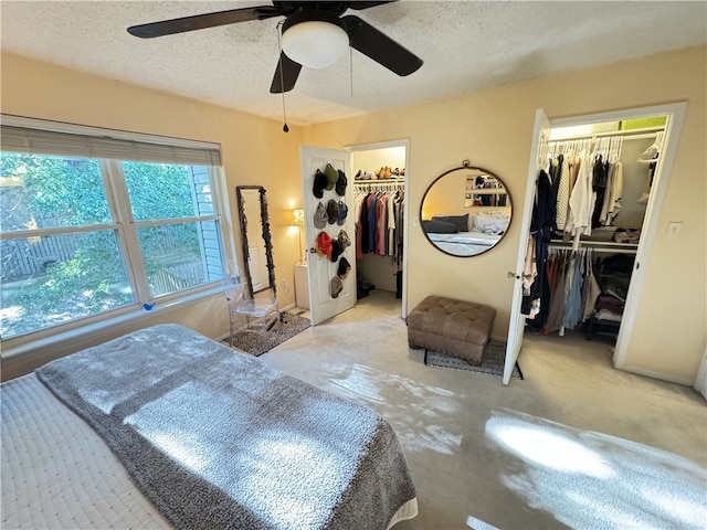 bedroom with a textured ceiling, light colored carpet, and ceiling fan