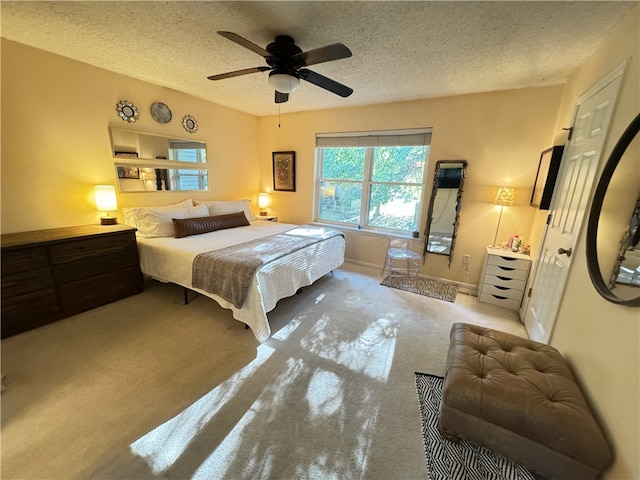 bedroom featuring a textured ceiling, light colored carpet, and ceiling fan