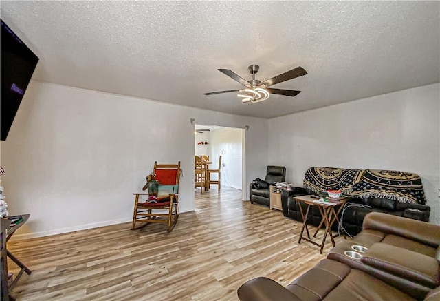 living room featuring a textured ceiling, light hardwood / wood-style floors, and ceiling fan