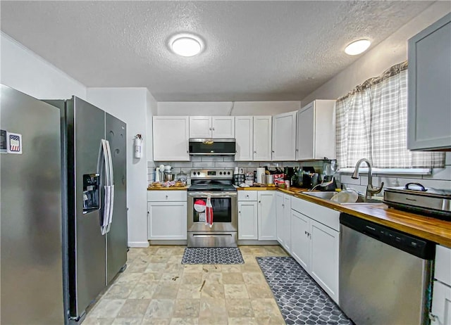 kitchen featuring wooden counters, sink, appliances with stainless steel finishes, tasteful backsplash, and white cabinetry