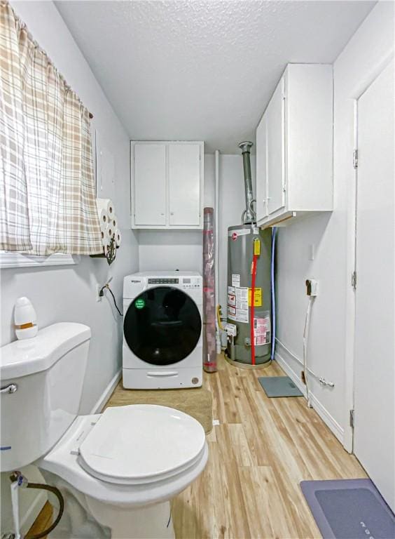 bathroom featuring gas water heater, wood-type flooring, a textured ceiling, and washer / clothes dryer