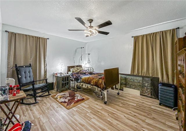 bedroom featuring ceiling fan, light hardwood / wood-style floors, and a textured ceiling