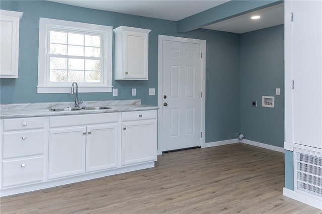 kitchen with beamed ceiling, sink, white cabinets, and light wood-type flooring