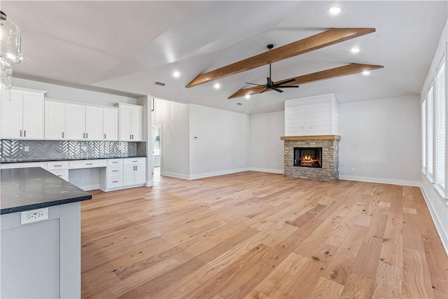 unfurnished living room with lofted ceiling with beams, ceiling fan, light hardwood / wood-style floors, and a fireplace