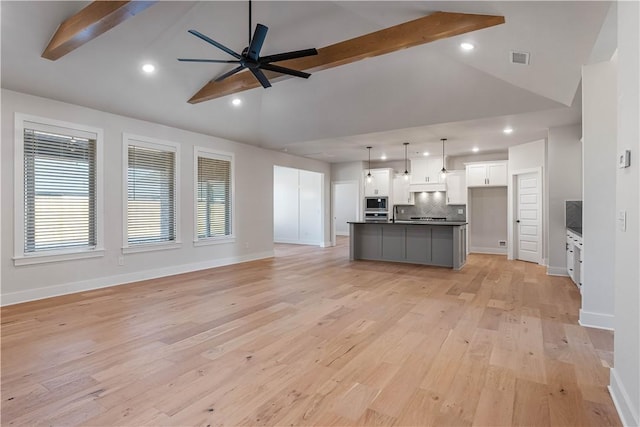 unfurnished living room featuring beam ceiling, light hardwood / wood-style floors, ceiling fan, and a healthy amount of sunlight