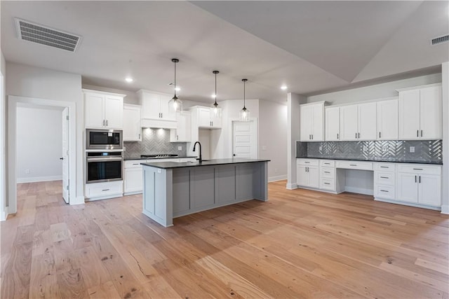 kitchen featuring built in microwave, white cabinetry, hanging light fixtures, oven, and vaulted ceiling