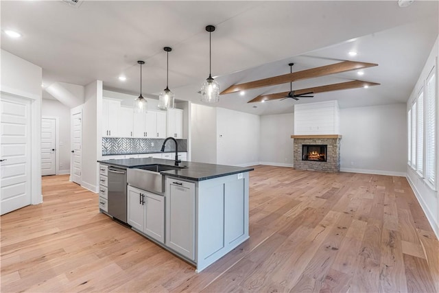 kitchen featuring a kitchen island with sink, sink, vaulted ceiling with beams, ceiling fan, and white cabinetry