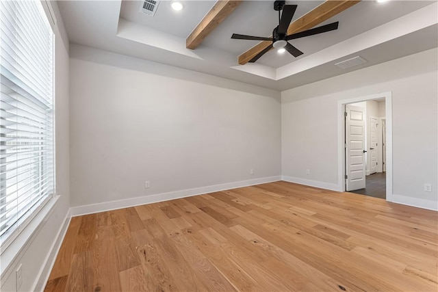 unfurnished room with beam ceiling, ceiling fan, a tray ceiling, and hardwood / wood-style flooring