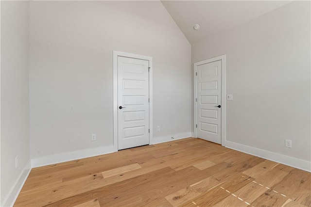 spare room featuring wood-type flooring and high vaulted ceiling