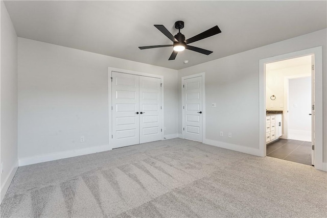 unfurnished bedroom with carpet, a closet, ceiling fan, and ensuite bathroom