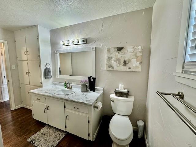 bathroom featuring hardwood / wood-style flooring, vanity, toilet, and a textured ceiling