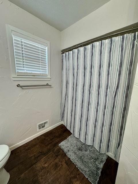 bathroom featuring wood-type flooring, toilet, and curtained shower