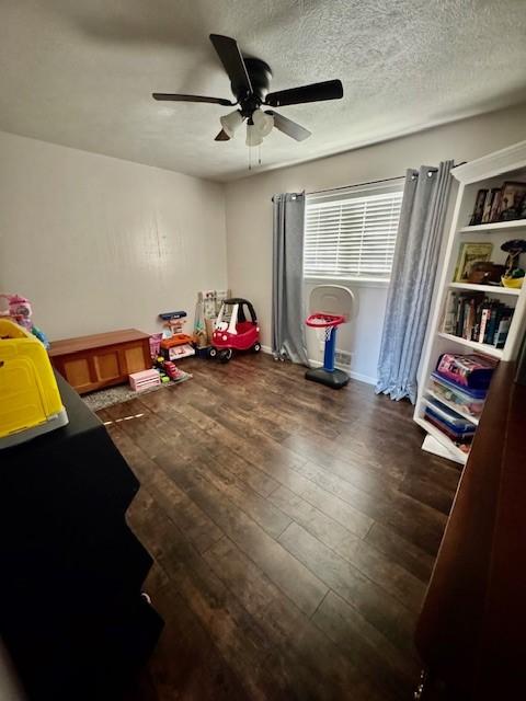 bedroom featuring ceiling fan, dark hardwood / wood-style floors, and a textured ceiling