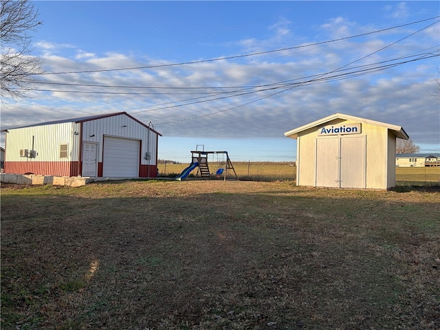 view of yard with a playground, a garage, and an outdoor structure