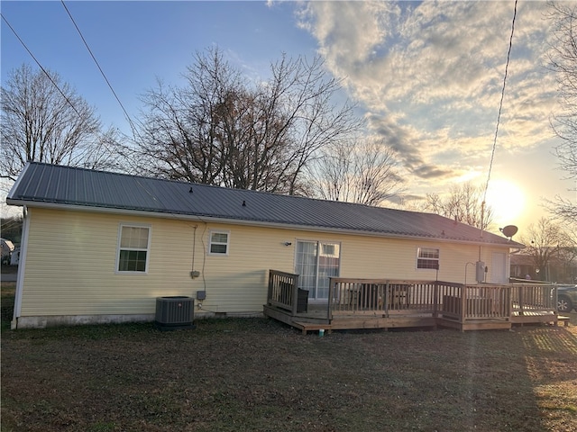 back house at dusk featuring central air condition unit and a deck