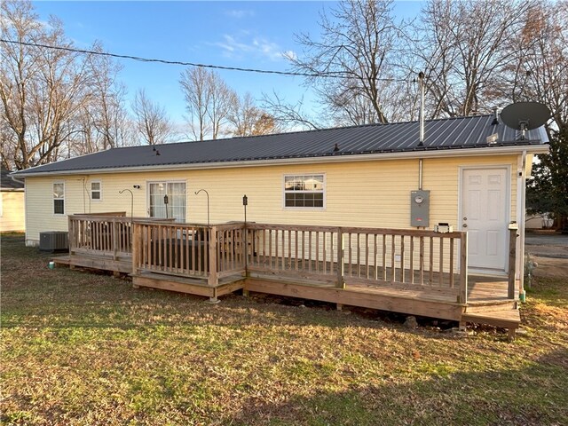 rear view of house with central air condition unit, a wooden deck, and a lawn