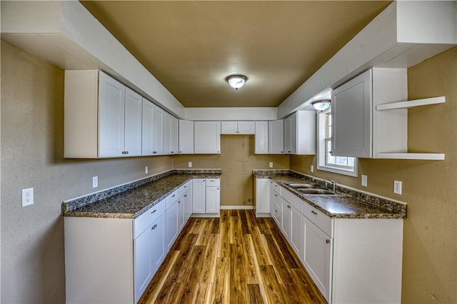 kitchen with dark stone countertops, sink, white cabinets, and dark hardwood / wood-style floors