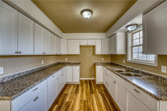 kitchen with white cabinetry, sink, and hardwood / wood-style floors