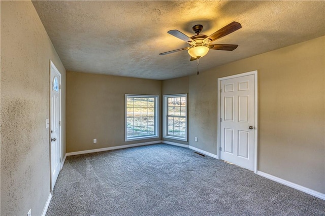 carpeted spare room featuring a textured ceiling and ceiling fan