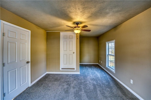 unfurnished bedroom featuring a textured ceiling, dark carpet, and ceiling fan