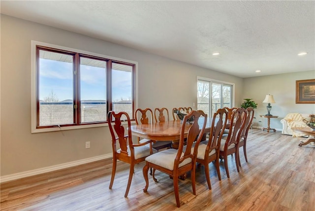 dining space with light wood-type flooring and a textured ceiling