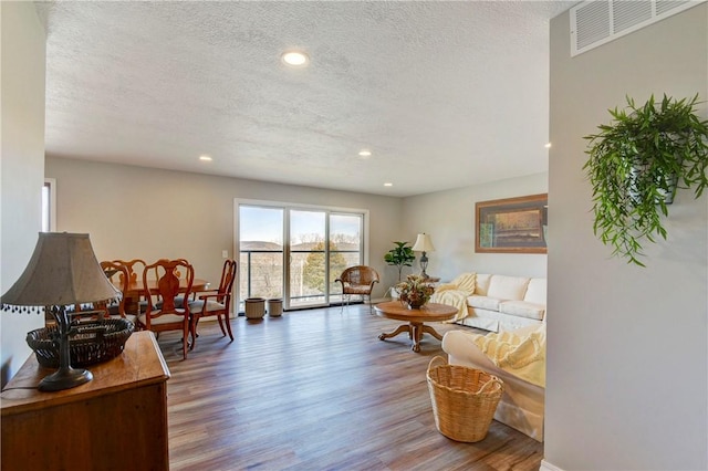 living room with hardwood / wood-style floors, a baseboard radiator, and a textured ceiling