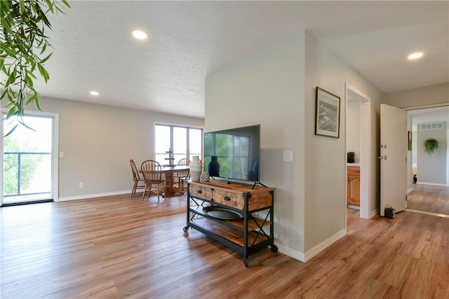 corridor featuring a textured ceiling, light hardwood / wood-style floors, and a wealth of natural light