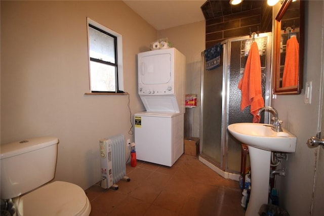 bathroom featuring tile patterned floors, an enclosed shower, radiator, toilet, and stacked washer / drying machine