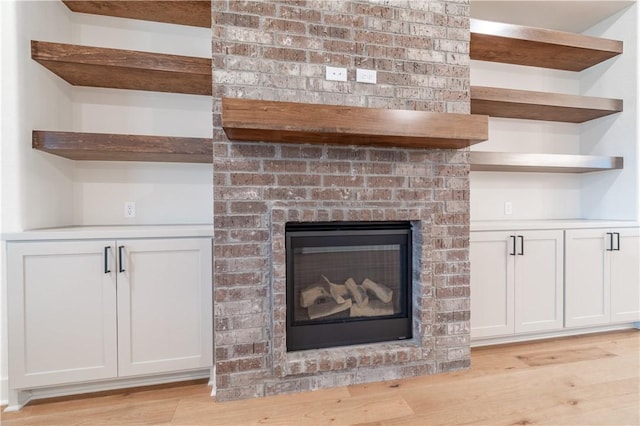 interior details with wood-type flooring and a brick fireplace