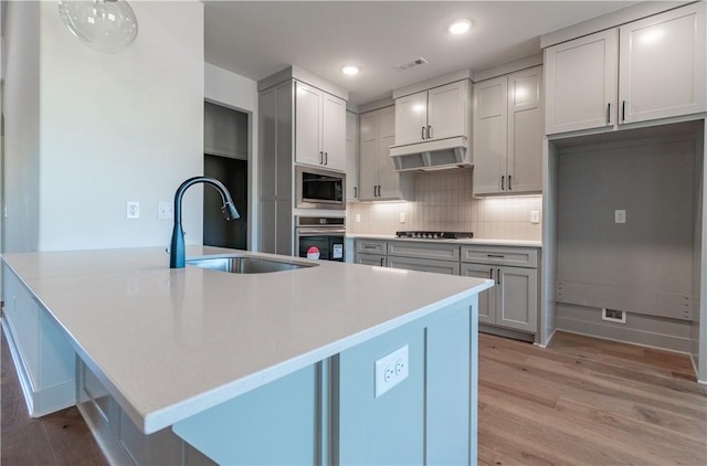 256 Fiori St, Springdale, AR 72762 - kitchen featuring appliances with stainless steel finishes, under cabinet range hood, light wood-type flooring, tasteful backsplash, and light countertops
