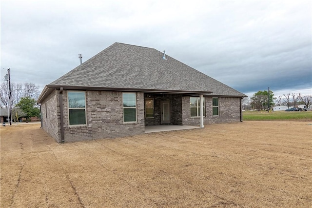 256 Fiori St, Springdale, AR 72762 - rear view of property featuring a shingled roof, a patio area, brick siding, and a lawn