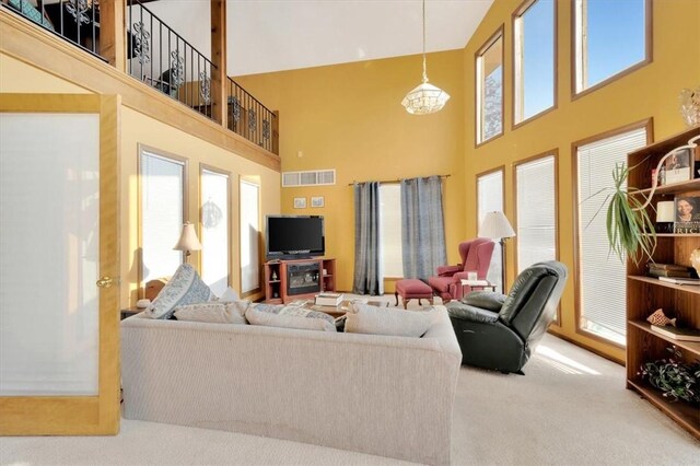 living room with a notable chandelier, carpet floors, and a high ceiling