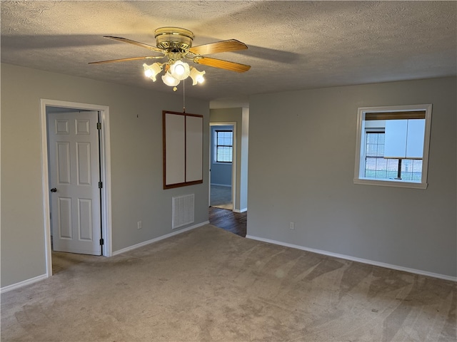 carpeted empty room with ceiling fan and a textured ceiling