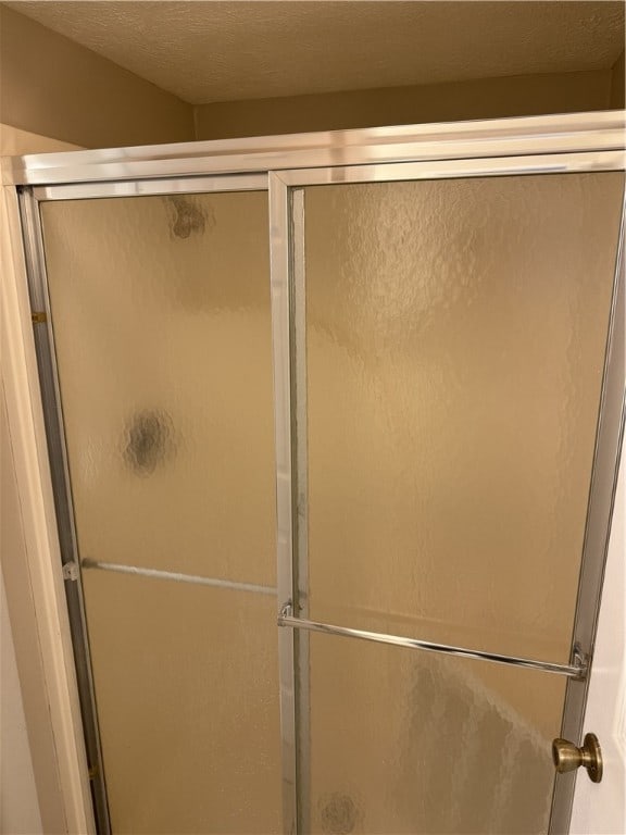 bathroom with a textured ceiling and an enclosed shower