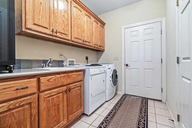 laundry room with washer and clothes dryer, sink, light tile patterned flooring, and cabinets