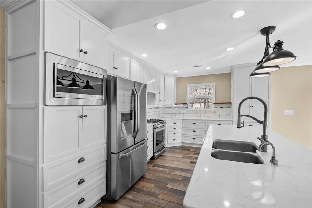 kitchen with sink, white cabinetry, tasteful backsplash, decorative light fixtures, and appliances with stainless steel finishes