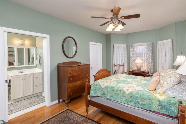 bedroom with connected bathroom, light hardwood / wood-style floors, ceiling fan, and sink