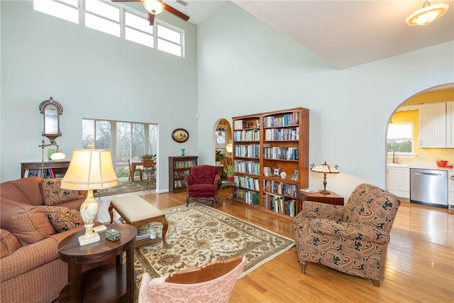 living room with light hardwood / wood-style floors, high vaulted ceiling, ceiling fan, and sink