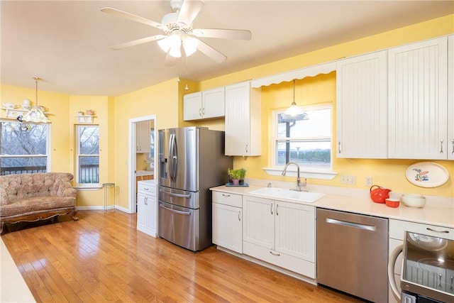 kitchen with white cabinets, sink, stainless steel appliances, and hanging light fixtures