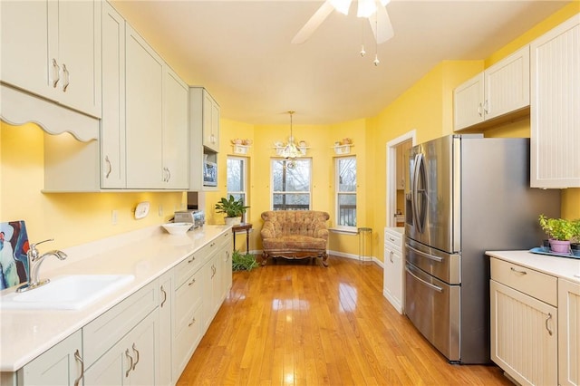 kitchen with pendant lighting, white cabinetry, stainless steel refrigerator, and sink