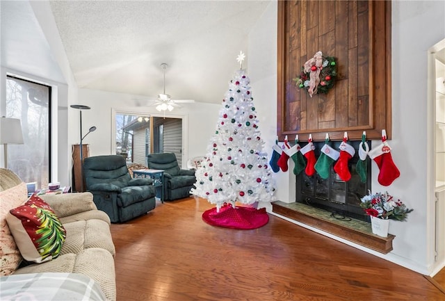 living room featuring ceiling fan, wood-type flooring, a textured ceiling, and vaulted ceiling