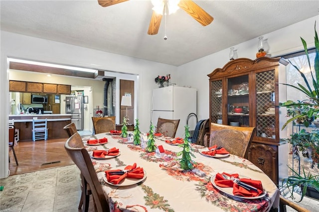 dining room with a textured ceiling, light wood-type flooring, and ceiling fan