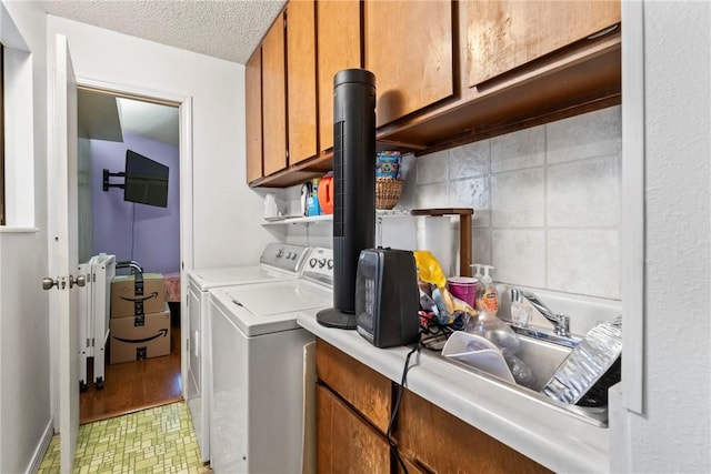 washroom with washer and dryer, sink, cabinets, and a textured ceiling