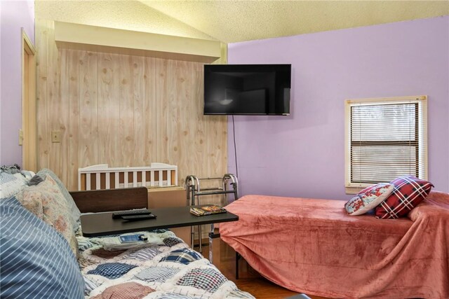 bedroom with wood-type flooring, a textured ceiling, and lofted ceiling