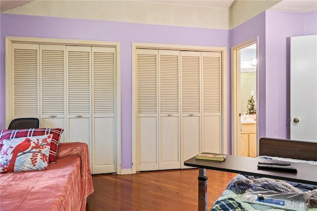 bedroom with multiple closets, dark hardwood / wood-style flooring, ensuite bath, and a textured ceiling