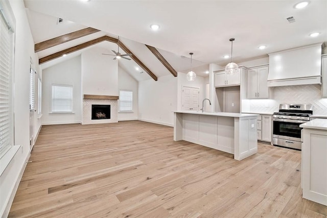 kitchen featuring custom exhaust hood, tasteful backsplash, decorative light fixtures, stainless steel range oven, and white cabinetry