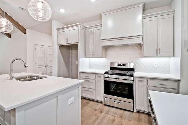 kitchen with stainless steel range with gas cooktop, sink, hanging light fixtures, tasteful backsplash, and beamed ceiling