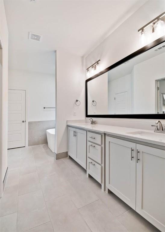 bathroom with tile patterned flooring, vanity, and a bathtub