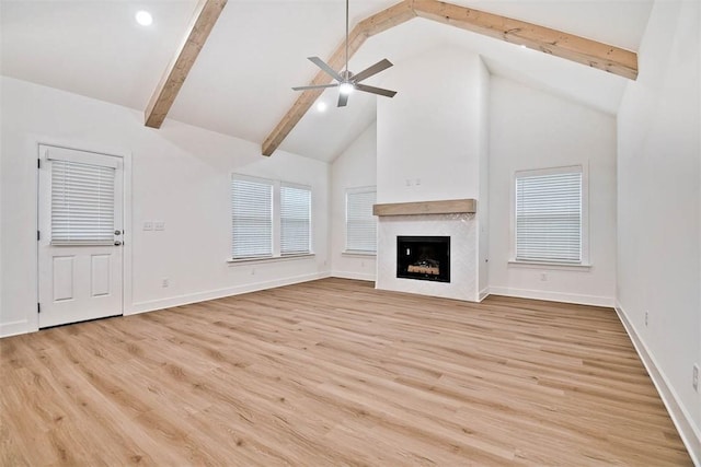 unfurnished living room featuring ceiling fan, high vaulted ceiling, light hardwood / wood-style floors, and beamed ceiling